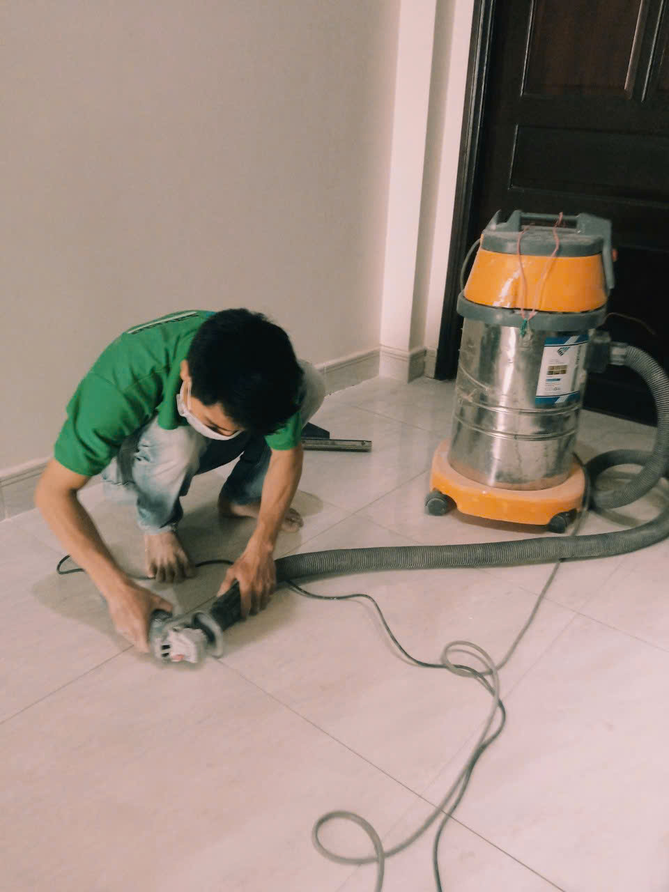 Thợ dùng máy mài và máy hút bụi thi công chuyên nghiệp