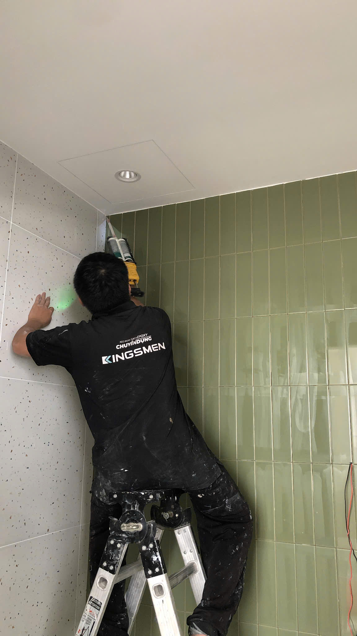 Thi công keo ron tường phòng tắm — làm việc trên cao bằng thang chuyên dụng